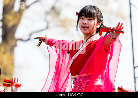Hinokuni Yosakoi Dance Festival. Lächelnd kind Tänzer, Mädchen in rosa Kostüm mit hängenden transparente Ärmel, Holding naruko, Arme ausgestreckt. Stockfoto