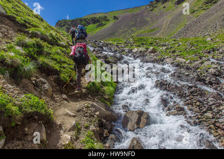 Bergtouristen fahren bergauf entlang des turbulenten Flusses in den Bergen des Kaukasus Stockfoto