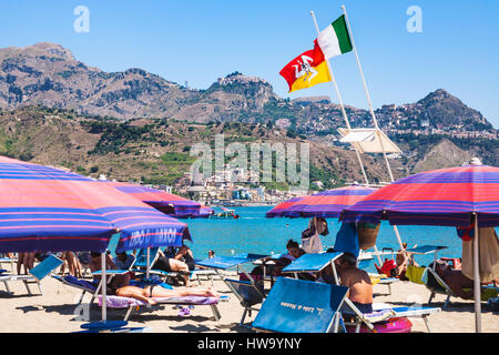 GIARDINI NAXOS, Italien - 8. Juli 2011: Flaggen über Menschen in städtischen Strand von Giardini Naxos-Stadt. Naxos wurde gegründet von Thucles die chalkidischen 734 v. Chr. Stockfoto