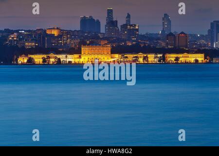 Türkei, Istanbul, Dolmabahce Palast, Nachtansicht von einem beleuchteten Palast vor einem modernen städtischen Bereich am Meer Stockfoto