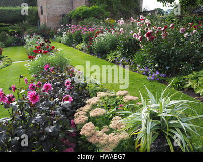 Chenies Manor Garten, Buckinghamshire. Der versunkene Garten Dahlie anzeigen in voller Blüte. Querformat, lebendige Pflanze Grenzen und Rasen in Richtung Pavillon. Stockfoto