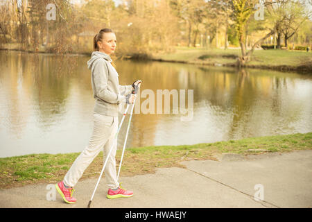 Hübsche junge Frau posiert mit die Stöcke für nordic walking im Park. Horizontal im Freien gedreht. Stockfoto