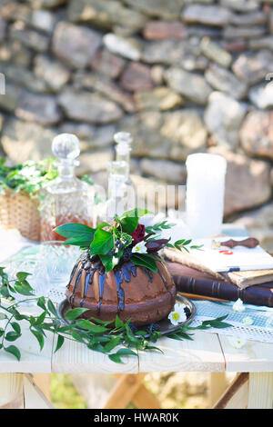 Cocolate Kuchen verziert mit Blumen und drei Whiskey Dekanter gegen einen hellgrauen Hintergrund mit Textfreiraum Stockfoto