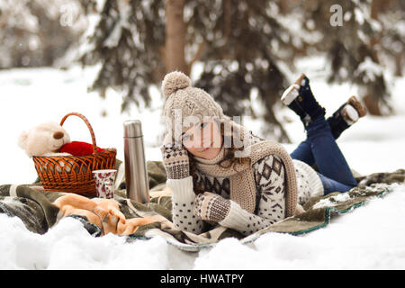 Niedlich, glücklich, leichte Mädchen sitzt auf einer Decke im Winter in der Kälte, Schnee, Fosest, Wald und Trinkbecher warmen Tee, Hintergrund, wenig, Umrech- Stockfoto