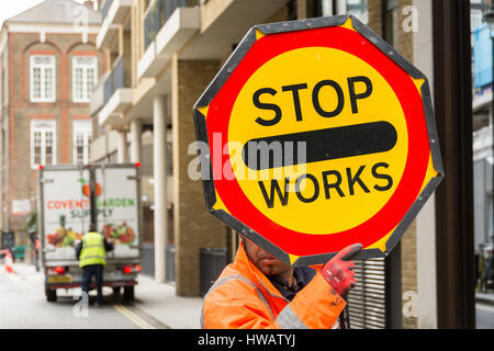 Ein Arbeiter hält ein Schild mit "Stop Works" in Soho, London, UK Stockfoto