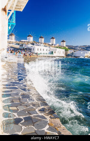 Plätschernden Wellen und berühmten Mykonos Windmühlen in goldenen Nachmittag Licht, Insel Mykonos, Kykladen, Griechenland Stockfoto