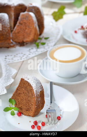 Frisch gebackener ringförmige Kuchen mit Schokolade, so genannte "Gugelhupf" in Österreich und Deutschland, mit einer Tasse Cappuccino serviert Stockfoto