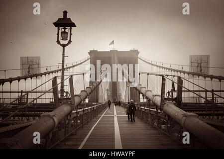 Zu Fuß auf der Brooklyn Bridge an einem nebligen Tag im Zentrum von Manhattan New York City. Stockfoto