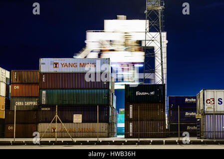 See-Container stapeln sich am Frachthafen, während hinter ein Kran bewegt. Stockfoto