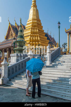 Bangkok, Thailand. 14. November 2006. Ein Touristen-paar unter einem Regenschirm bewundern Sie eines der beiden goldenen Pagoden (Phra Chedis) im Tempel des Smaragd-Buddha zusammengesetzten (Wat Phra Kaew). Im Grand Palace in Bangkok, bis ins 18. Jahrhundert Komplex sie sind mit Lack, bedeckt mit Blattgold, bemalt und bunte Statuen der Affe Krieger, Figuren aus der thailändischen Ramakien-Epos, um ihre Basis haben. Thailand ist ein beliebtes Touristenziel geworden. Bildnachweis: Arnold Drapkin/ZUMA Draht/Alamy Live-Nachrichten Stockfoto