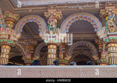 Köpfe von Körperregionen Gläubigen sichtbar unter der hell eingerichteten Burmesen Teak Torbögen in der Hindutempel Shri Swaminarayan in Ahmedabad, Indien Stockfoto