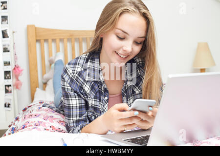 Teenager-Mädchen mit Handy während der Hausaufgaben Stockfoto