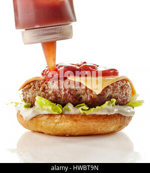 Hinzufügen von Tomatensauce auf Burger zu kochen. Burger-Vorbereitung isoliert auf weißem Hintergrund Stockfoto