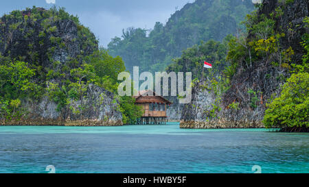 Bambushütte zwischen einigen Felsen unter Regen im Bay, Painemo Inseln, Raja Ampat, West-Papua, Indonesien Stockfoto