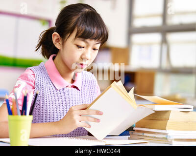 asiatische Grundschüler Lesen eines Buches im Unterricht. Stockfoto