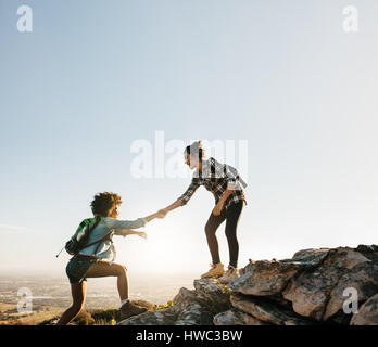 Wandern Freundinnen helfen sich gegenseitig in Bergen. Junge weibliche Wanderer Freund helfen, beim Wandern in den Bergen. Stockfoto