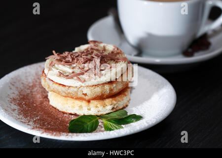Kuchen auf Teller in der Nähe von Kaffee auf dunklen Holztisch Stockfoto