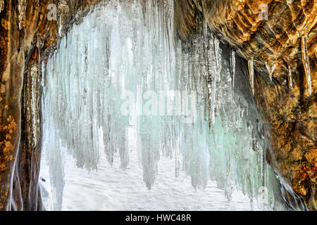 Lange Eiszapfen am Bogen der kleinen Grotte in küstennahen Felsen. Blick aus dem Inneren. Der Baikalsee. Olchon Stockfoto