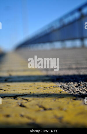 Zum Zeitpunkt des Sonnenuntergangs mit der Reflexion von einem Zaun auf der Brücke Varadin von gelben Band auf dem Bürgersteig über der Donau in N fotografiert. Stockfoto