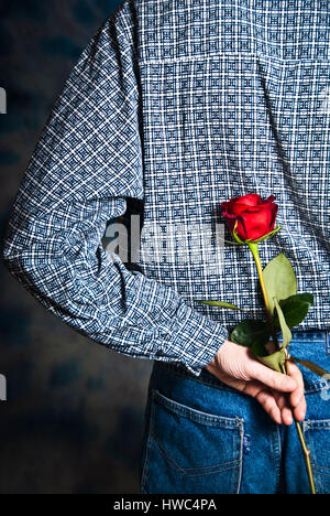 Mann mit einer roten rose in der hand hinter seinem zurück warten, um es als ein romantisches Geschenk Stockfoto
