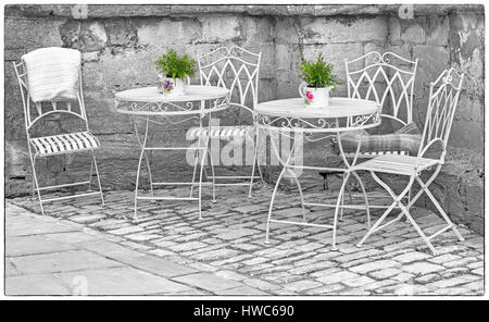 Cirencester - reich verzierten schmiedeeisernen Tische und Stühle mit Blumentöpfen in einer Ecke des Cirencester, Gloucestershire im März Stockfoto