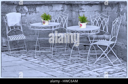 Cirencester - reich verzierten schmiedeeisernen Tische und Stühle mit Blumentöpfen in einer Ecke des Cirencester, Gloucestershire im März Stockfoto