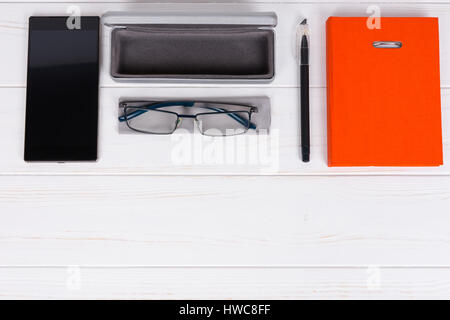 Tagebuch mit einem Stift für die Organisation eines Zeitplans, stilvolle Gläser und offenen Fall für Gläser in der Nähe von Handy auf weißer Holztisch Stockfoto