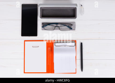 Öffnen Sie Tagebuch mit einem Stift für die Organisation eines Zeitplans, stilvolle Gläser und offenen Fall für Gläser in der Nähe von Handy auf weißer Holztisch Stockfoto