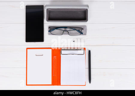 Öffnen Sie Tagebuch mit einem Stift für die Organisation eines Zeitplans, Gläser und offenen Fall für Gläser in der Nähe von Handy auf weißer Holztisch Stockfoto