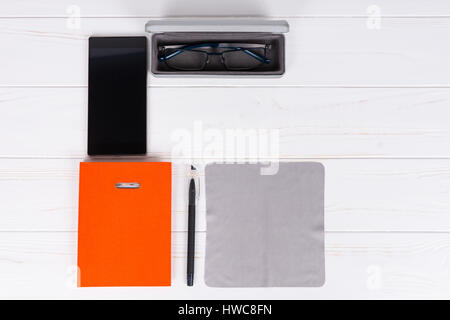 Orange-Tagebuch mit einem Stift für die Organisation eines Zeitplans Gläser in offenen Fall in der Nähe von Handy auf weißer Holztisch Stockfoto