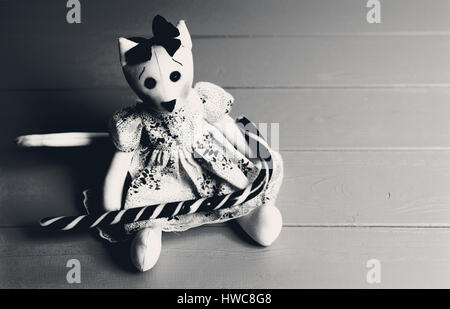 Schwarz / weiß Bild von hausgemachten Spielzeug in Form einer Katze in einem Kleid mit Zuckerstange auf Holzbrett Stockfoto