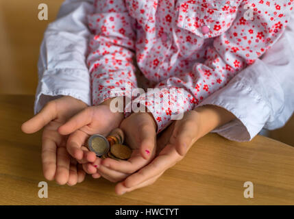 Kinder halten Münzen Geld in ihren Händen. Symbolische Foto für das Speichern und den Umgang mit Geld lernen., Kinder Zweisimmen Münzen von Geld in Ihren lässt. Stockfoto
