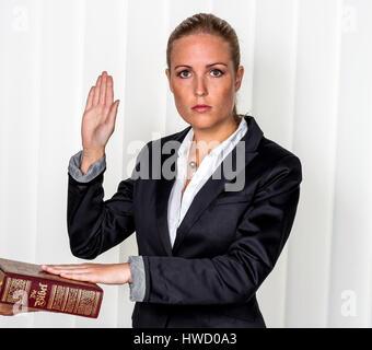 Eine Frau sagt als Zeuge vor Gericht in ein gerichtliches Verfahren. Wird vereidigt und schwört auf die Bibel., Eine Frau Sagt als Zeuge Bei Gericht in Einem Zerlett Stockfoto