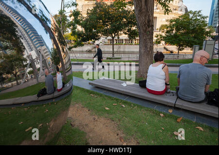 23.09.2016, Singapur, Republik Singapur - Besucher sitzen auf einer Parkbank neben der großen kugelförmigen reflektierende Kugeln in Singapur. Stockfoto