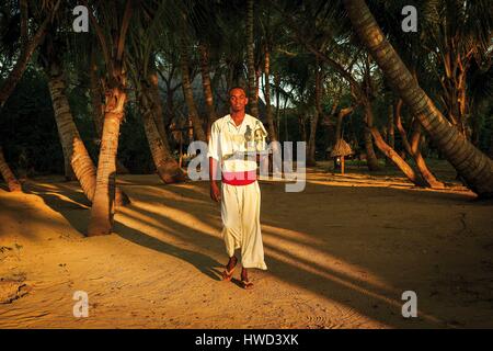 Tanzania, Zanzibar, Chapwani, Chapwani Private Island Resort, Server eines Luxus-Hotels mit einem Willkommens-Cocktail am Strand Stockfoto