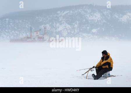 Kanada, Québec, Saguenay, La Baie, weißen Fischen Dorf Anse ein Benjamin, ein Mann Angeln auf dem Eis, Eisbrecher im Hintergrund Stockfoto