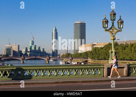 Vereinigtes Königreich, London, Westminster, Westminster Bridge, Türme, Gebäude im Bau und die Frau auf dem Bürgersteig Musik hören mit Kopfhörern in joggen Outfit Stockfoto