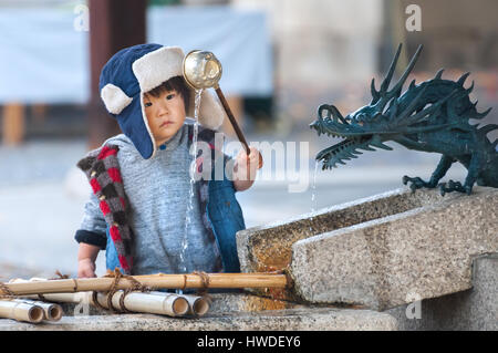 KYOTO, JAPAN-NOV 2016 - ein Junge schaufeln Wasser aus einem Brunnen Reinigung an einem Tempel in Kyoto, Japan Stockfoto