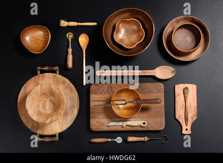 High Angle Stillleben View Sammlung von Holz Küche-Objekten - Holz Schalen schneiden Bretter, Löffel und andere Utensilien auf dunklen schwarzen Hintergrund