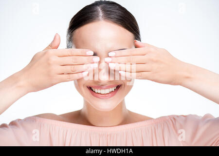 Porträt der lächelnde Frau schließt die Augen mit Händen isoliert auf weiss Stockfoto