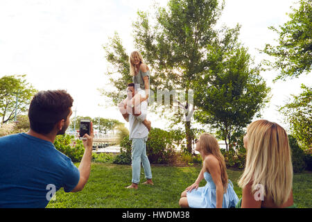 Junger Mann Fotografieren Schulter mit Freunden im park Stockfoto
