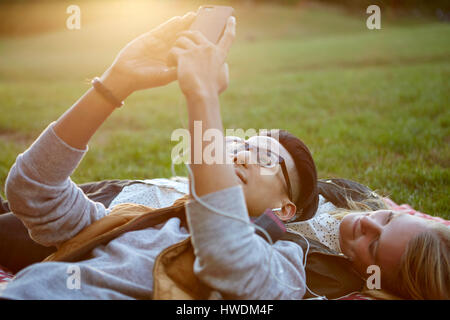 Paar auf der Picknickdecke im Park Kopfhörer Musik austauschen Stockfoto