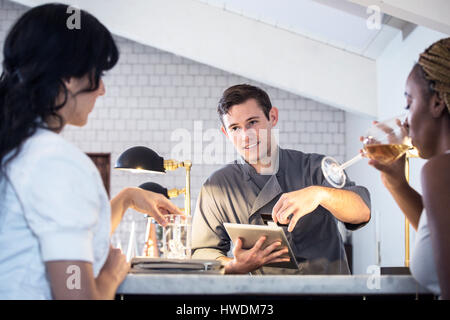 Barmann bedient Kunden in bar, Barkeeper mit digital-Tablette, Zahlung zu nehmen Stockfoto