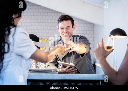 Barmann bedient Kunden in bar, Barkeeper mit digital-Tablette, Zahlung zu nehmen Stockfoto