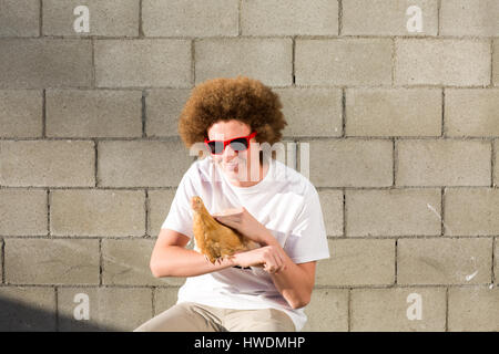 Porträt von Teenager mit roten Afro-Haar, mit Huhn Stockfoto