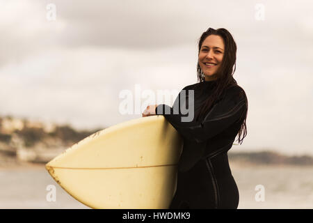 Junge Frau, die zu Fuß vom Meer entfernt, die Surfbretter Stockfoto