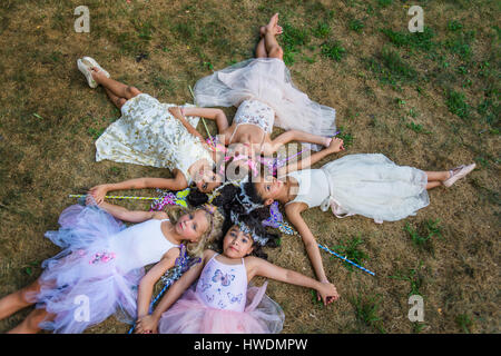 Gruppe junger Mädchen gekleidet wie Feen, liegen im Kreis, Köpfe zusammen Stockfoto