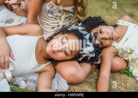 Gruppe junger Mädchen, gekleidet wie Feen, liegend auf dem Rasen Stockfoto