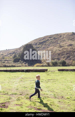 Jungen über grüne Hügel im Hintergrund laufen Stockfoto