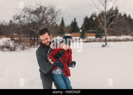 Vater und Tochter spielen im Schnee Stockfoto